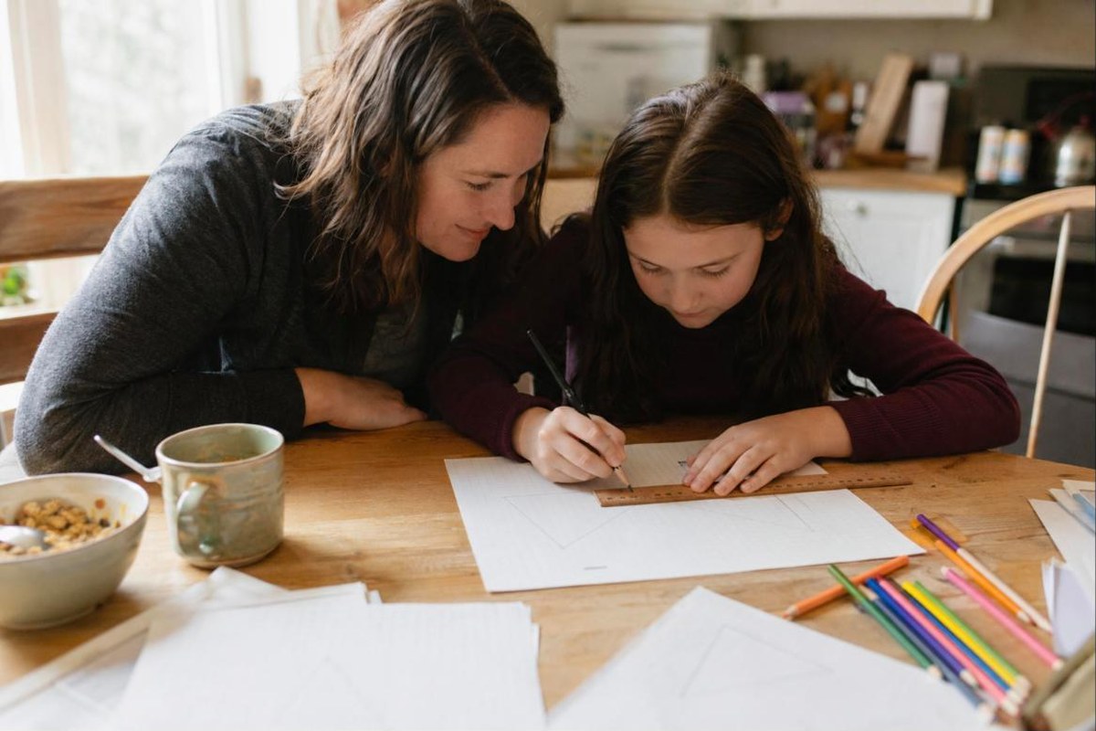 Homeschool student using a ruler to draw a triangle on grid paper while practicing geometry