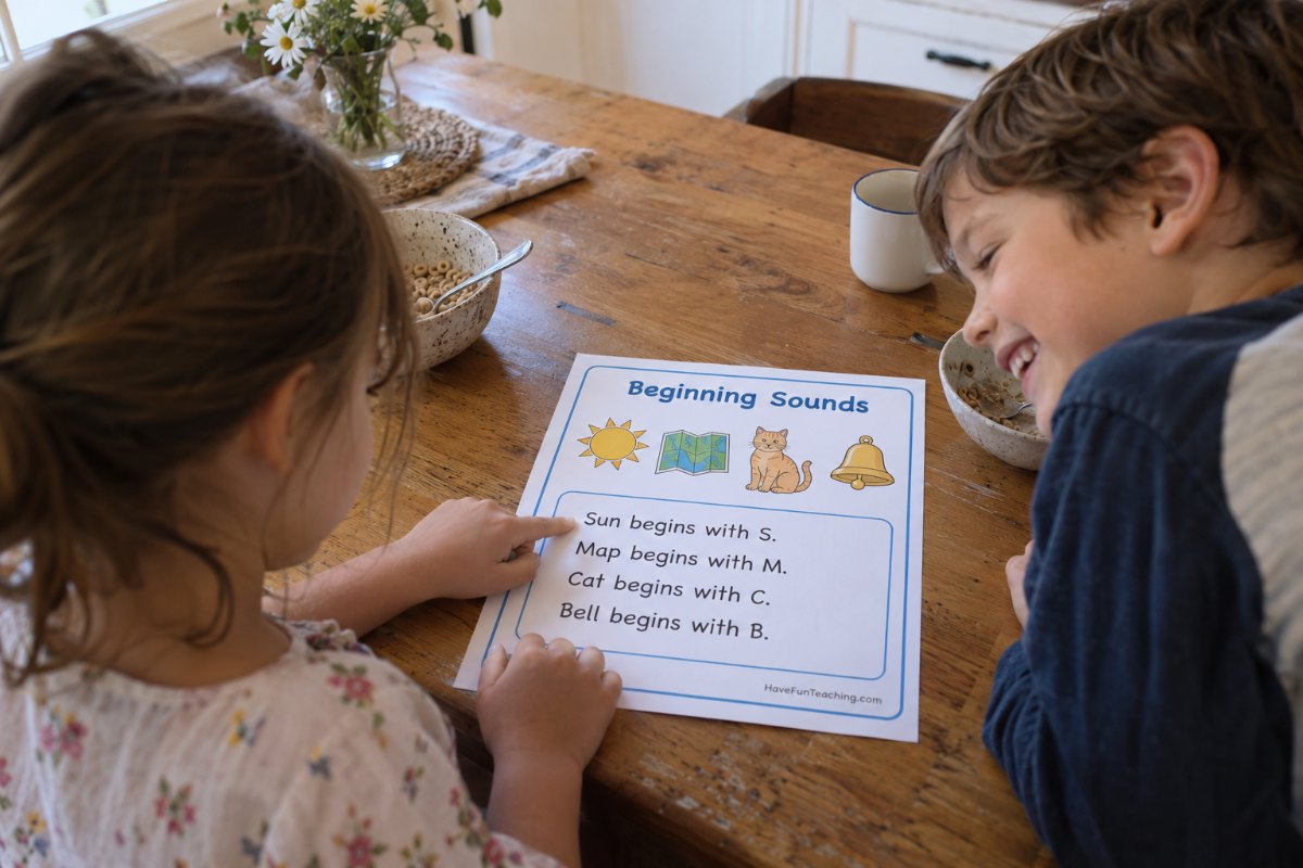 Two first graders using free phonics worksheets to sound out beginning sounds at the kitchen table